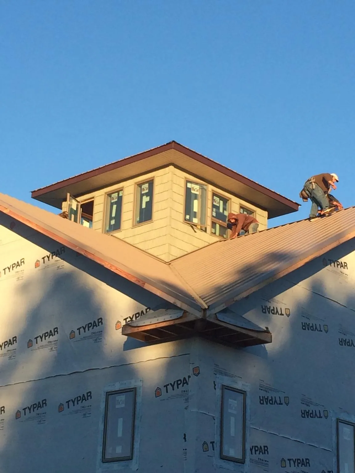 Roofers working around a rooftop cupola on a new metal roof at sunset — Roof Waterproofing in Longwood by Roofing Brothers